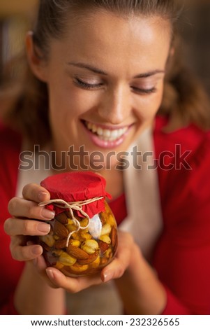 Portrait of happy young housewife holding jar with honey nuts