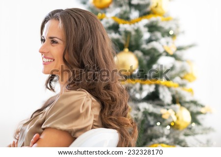 Profile portrait of happy young woman sitting near christmas tree