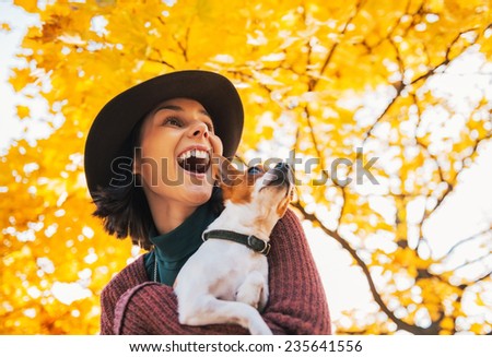 Portrait of happy young woman with dog outdoors in autumn looking on copy space