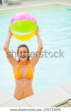 Portrait of smiling young woman with beach ball in pool