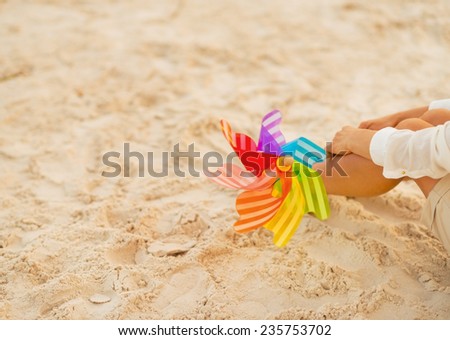 Closeup on young woman with colorful windmill toy sitting on beach at the evening