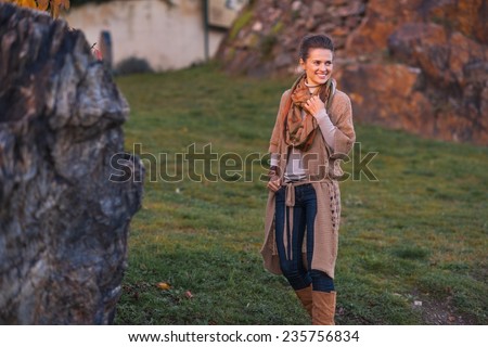 Happy young woman walking in autumn park in evening