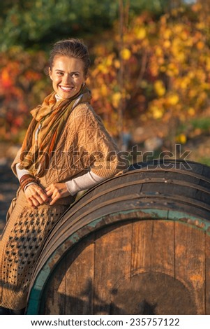 Smiling young woman near wooden barrel looking on copy space