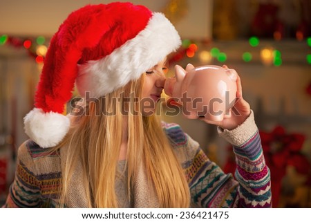Portrait of smiling teenager girl in santa hat with piggy bank