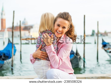 Portrait of happy mother and baby hugging on grand canal embankment in venice, italy