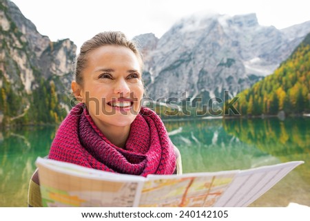 Portrait of happy young woman with map on lake braies in south tyrol, italy