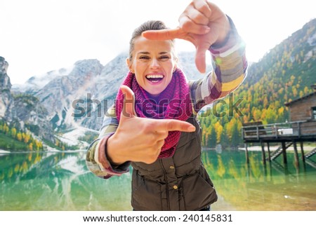 Portrait of smiling young woman on lake braies in south tyrol, italy framing with hands
