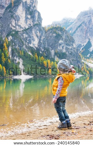 Child throwing stones while on lake braies in south tyrol, italy