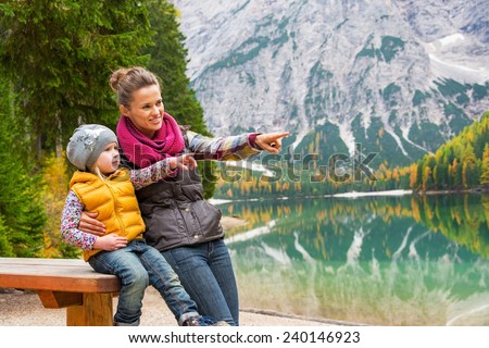 Portrait of happy mother and baby on lake braies in south tyrol, italy pointing on copy space