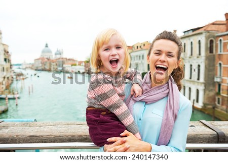 Portrait of happy mother and baby girl standing on bridge with grand canal view in venice, italy