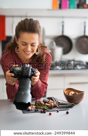 Happy female food photographer checking photos in camera