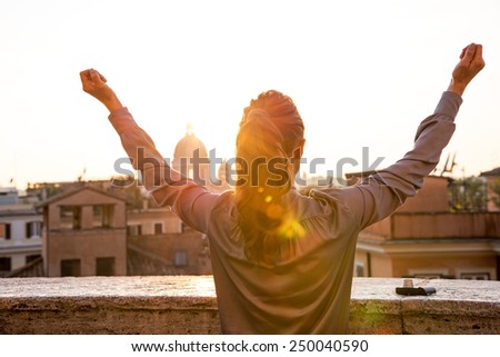 Young woman looking on rome panorama on sunset and rejoicing. rear view