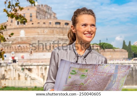 Portrait of happy young woman with map on embankment near castel sant\'angelo in rome italy