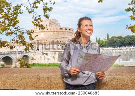 Portrait of happy young woman with map examining attractions on embankment near castel sant\'angelo in rome italy