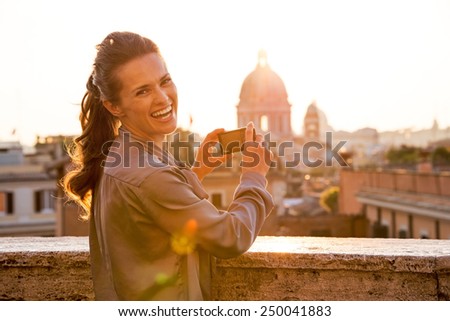 Young woman taking photo of rome panorama on sunset