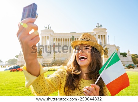 Happy young woman with italian flag making selfie on piazza venezia in rome, italy