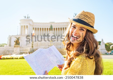 Portrait of happy young woman with map examining attractions on piazza venezia in rome, italy