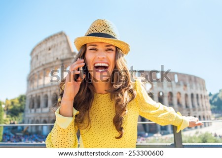 Smiling young woman talking cell phone in front of colosseum in rome, italy