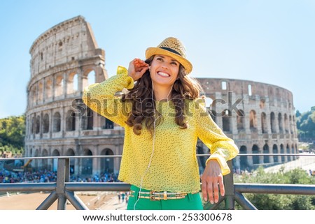 Happy young woman with audio guide in front of colosseum in rome, italy