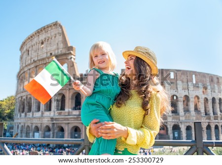 Happy mother and baby girl with italian flag in front of colosseum in rome, italy