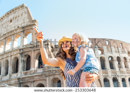 Happy mother and baby girl sightseeing near colosseum in rome, italy