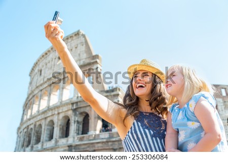 Happy mother and baby girl making selfie in front of colosseum in rome, italy
