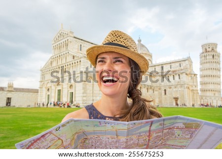 Smiling young woman with map on piazza dei miracoli, pisa, tuscany, italy