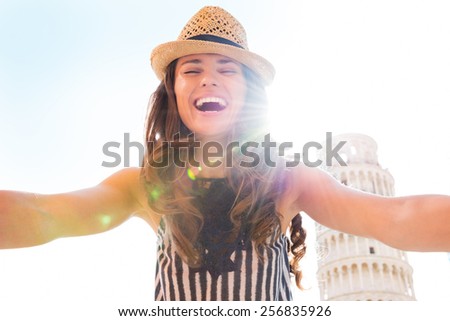 Happy young woman making selfie in front of leaning tower of pisa, tuscany, italy