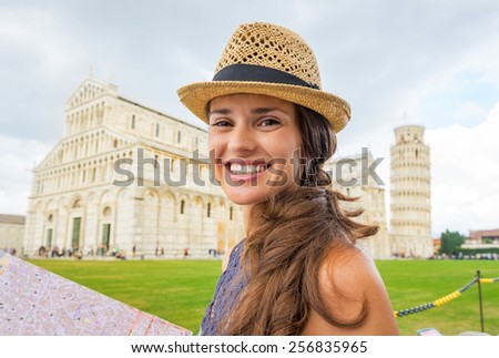 Portrait of happy young woman with map on piazza dei miracoli, pisa, tuscany, italy