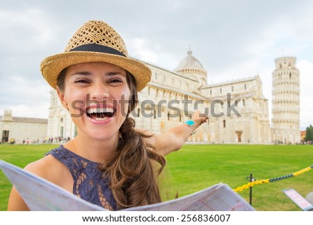 Happy young woman with map pointing on duomo di pisa, pisa, tuscany, italy