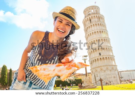Smiling young woman giving pizza in front of leaning tower of pisa, tuscany, italy