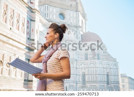 Young woman with map and audio guide in front of cattedrale di santa maria del fiore in florence, italy