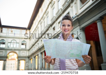 Portrait of happy young woman with map near uffizi gallery in florence, italy
