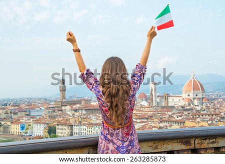 Young woman with flag rejoicing against panoramic view of florence, italy