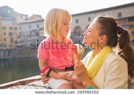 Happy mother and baby girl eating ice cream near ponte vecchio in florence, italy