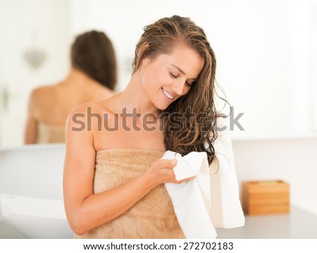Happy young woman wiping hair with towel in bathroom