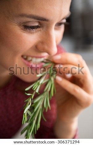 A woman smiles as she takes a little nip of some fresh rosemary. Impossible to resist the rich, earthy flavour of freshly-picked rosemary. The hard part will be deciding which dish to cook...