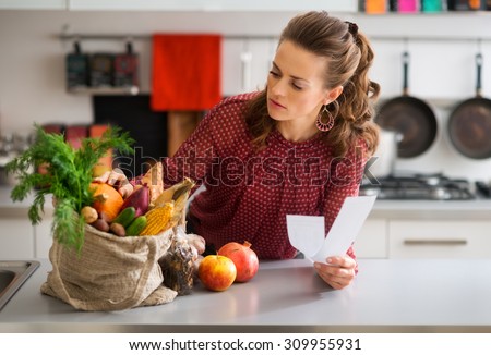 An elegant woman is leaning on the kitchen counter, checking the contents of her burlap bag which is filled with fresh autumn fruits and vegetables. She is double-checking that she has everything.