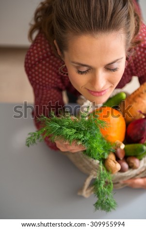 The heady aroma of fresh vegetables. There is nothing quite like it. A woman is closing her eyes with pleasure, smelling the delicate, earthy scent of the fall vegetables she has bought at the market.