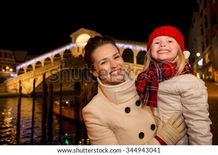 Modern family take the best of Christmas season by having a fascinating trip to Venice, Italy. Portrait of happy mother and daughter in the front of Rialto Bridge