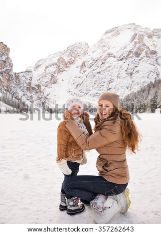 Winter leisure time spent outdoors among snowy peaks can turn the holidays into a fascinating journey. Portrait of mother and child spending time outdoors among snow-capped mountains