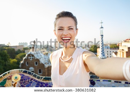 Refreshing promenade in unique Park Guell style in Barcelona, Spain. Happy young woman tourist taking selfie in Park Guell, Barcelona, Spain