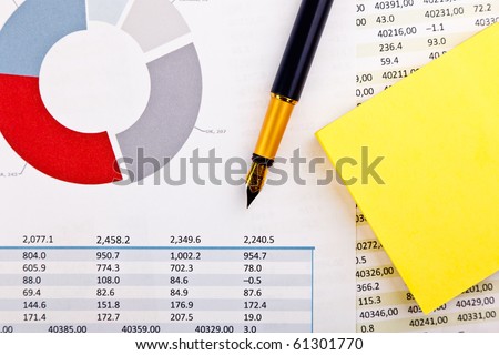ink pen, sticker and financial documents with charts