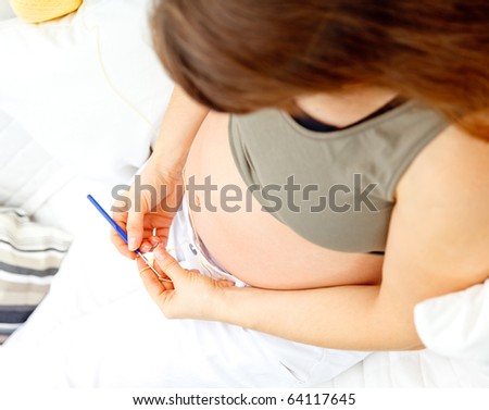 pregnant woman sitting on sofa and knitting for her baby