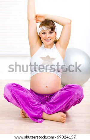 Smiling beautiful pregnant woman making gymnastics  at home