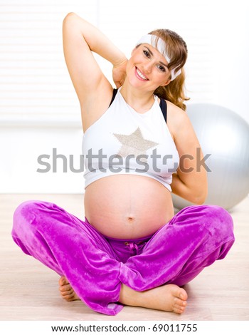 Smiling beautiful pregnant woman making gymnastics  at home