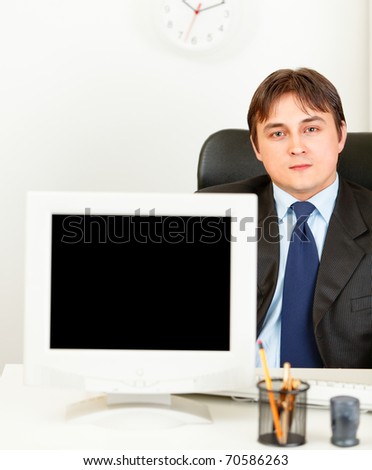 Modern business man sitting at office desk and showing monitors blank screen