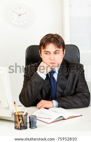 Pensive businessman man sitting at office desk and keep head on hand