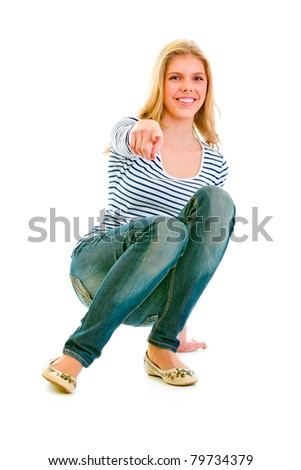 stock photo Smiling beautiful teen girl squatting and pointing finger at