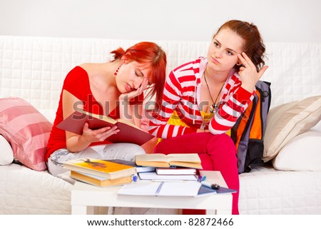 Two tired girlfriends bored to study at living room